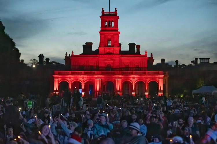 crowd gathered in front of Werribee Park Mansion at night