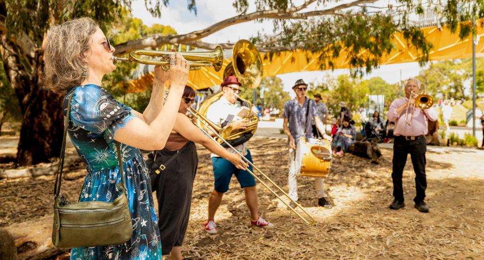 Brass band performing in front of orange bridge in Wyndham Park